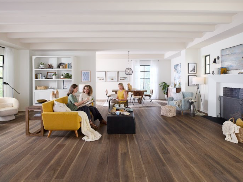 Three women sitting in a stylish living room with durable Pergo flooring